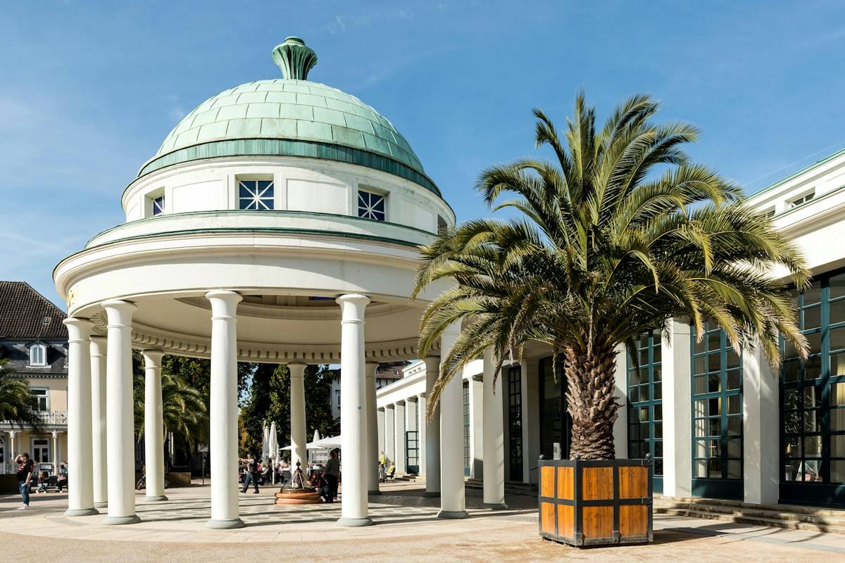White round pavilion with a green dome and a palm tree in a tub